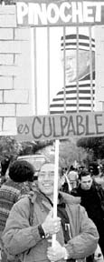 Una oponente a Pinochet muestra en Santiago una fotografa del
presidente Salvador Allende. A la derecha, cartel sobre el futuro que
el manifestante desea para el ex dictador n Fotos: Ap